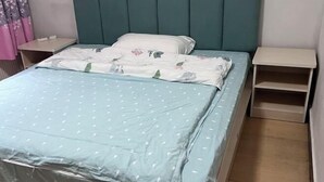 Un lit avec une couette à motifs floraux, une tête de lit de couleur turquoise et deux tables de chevet.