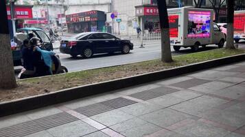 A street view with a sidewalk, trees, and a parked car.