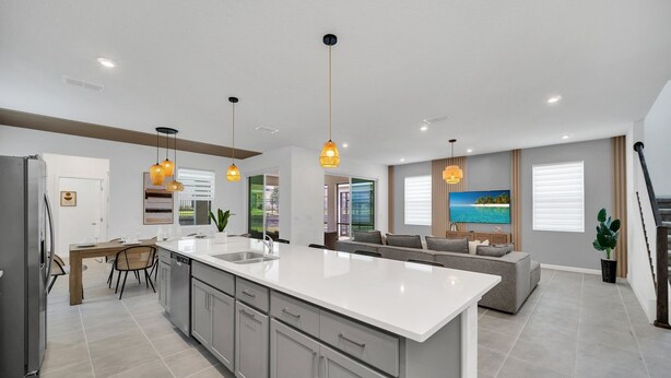 Una cocina moderna con una isla grande, iluminación colgante y un comedor con mesa y sillas.