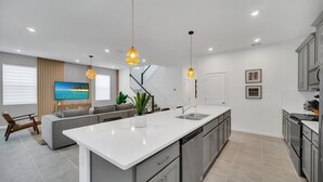 Una cocina moderna con una isla central, electrodomésticos integrados e iluminación colgante.