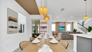 Un comedor moderno con una mesa de madera dispuesta para una comida, rodeada de sillas de mimbre.
