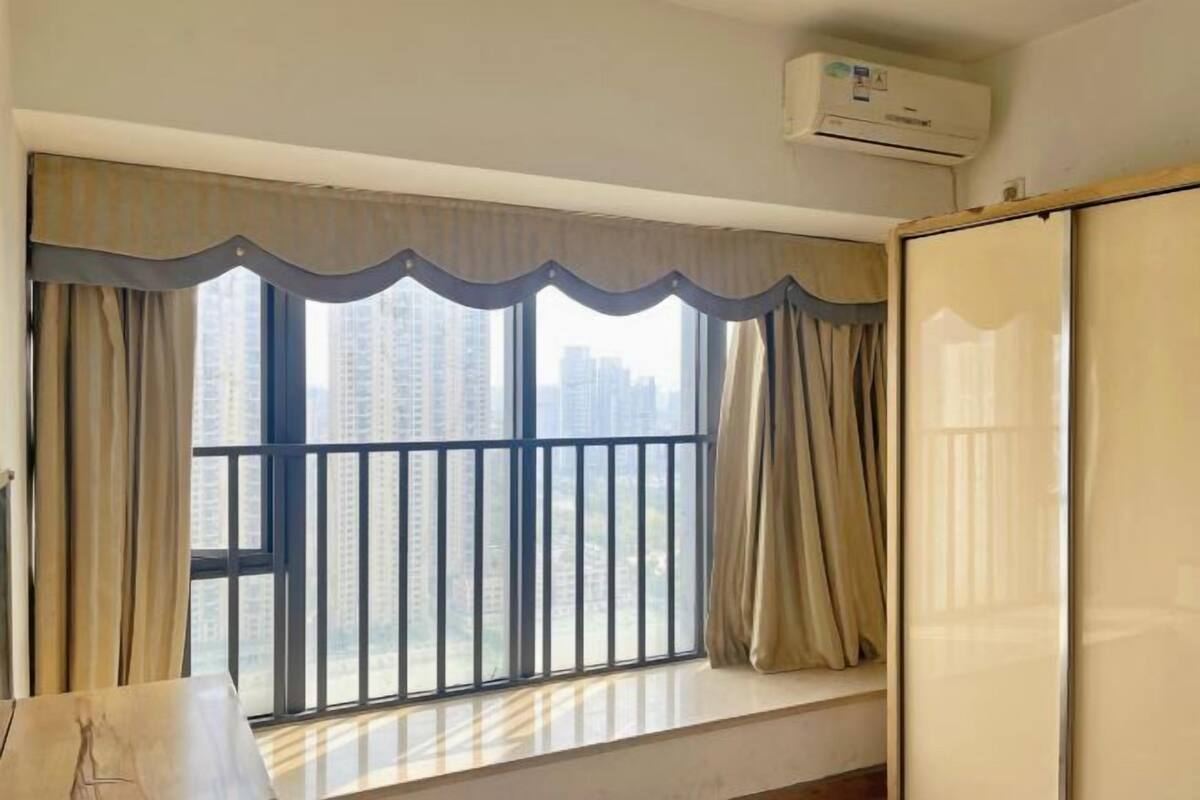 Una habitación con un ventanal grande, un balcón y un aire acondicionado.