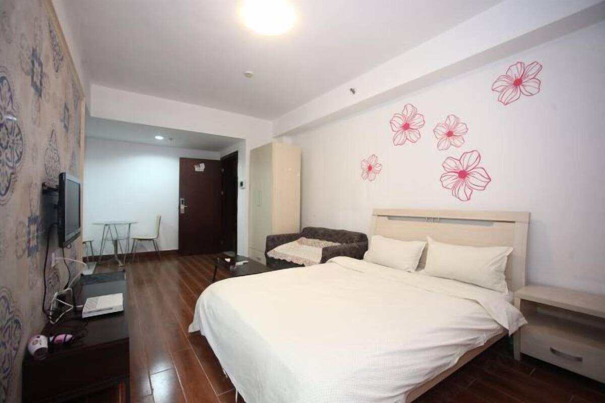 Un dormitorio con cama, televisor, escritorio y silla.