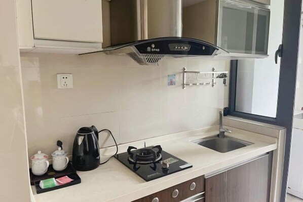 A compact kitchenette with a gas stove, a kettle, and a small sink. - YouJia Apartment (Foshan)
