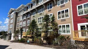 A multi-story residential building with a mix of siding colors and a central courtyard with trees. - Very Cute Studio Next To Ski Slope WiFi Village (Snowshoe)