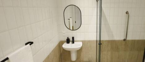 A bathroom with a white sink, a mirror, a towel rack, and a shower area.