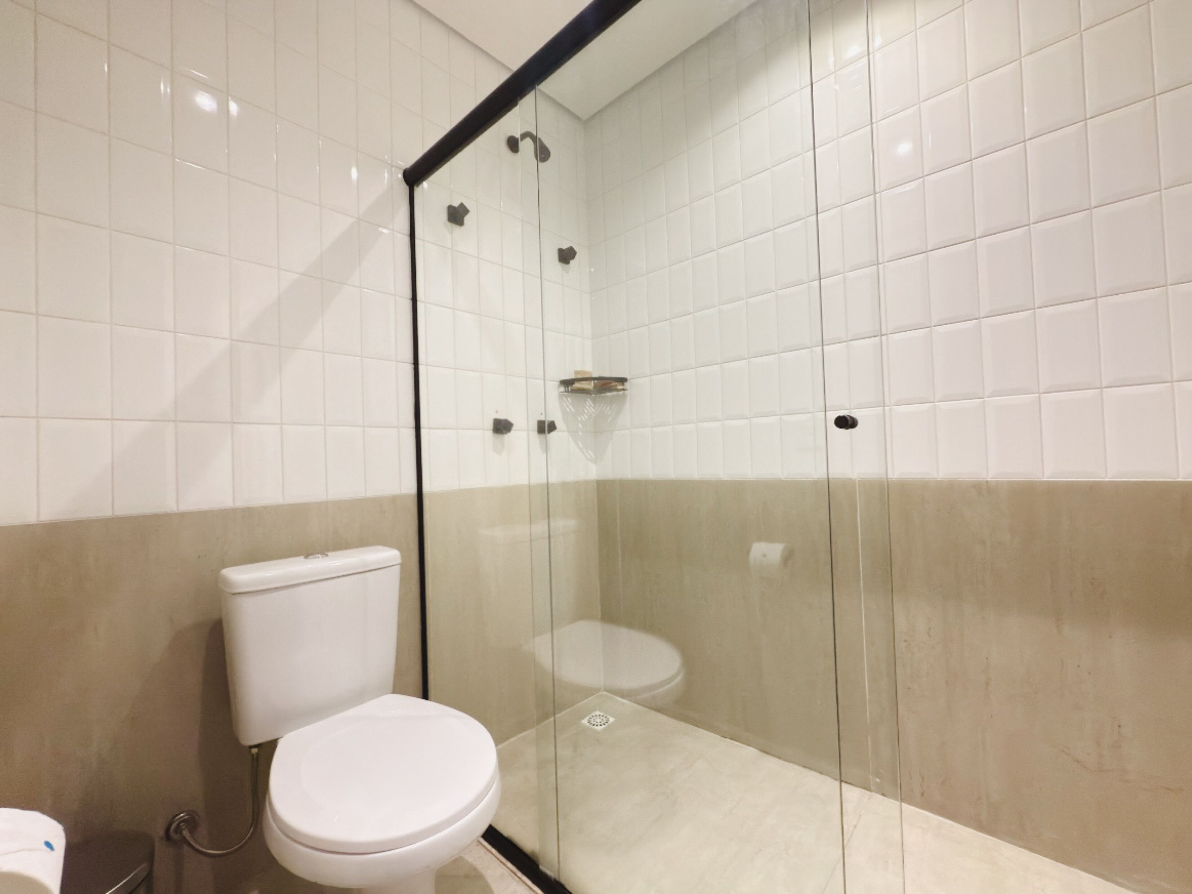 Un baño moderno con ducha acristalada, inodoro y lavamanos.