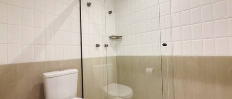 Un baño moderno con ducha acristalada, inodoro y lavamanos.