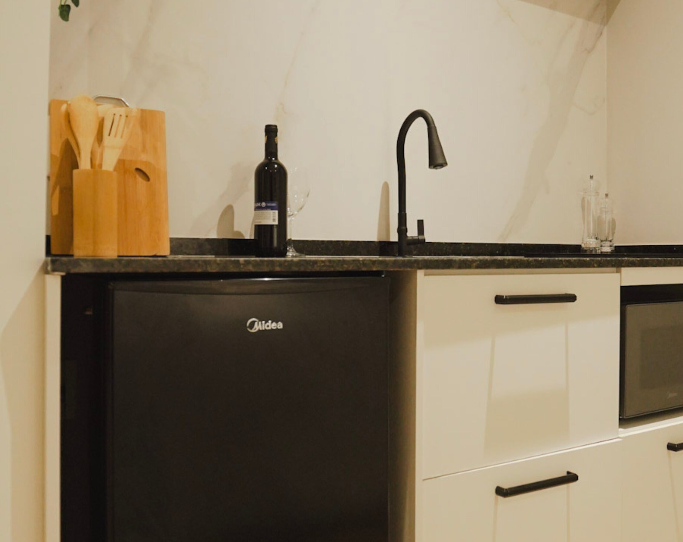 A compact kitchen with a black refrigerator, a sink, and a microwave.