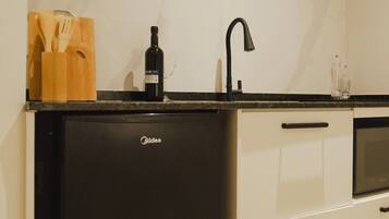 A compact kitchen with a black refrigerator, a sink, and a microwave.