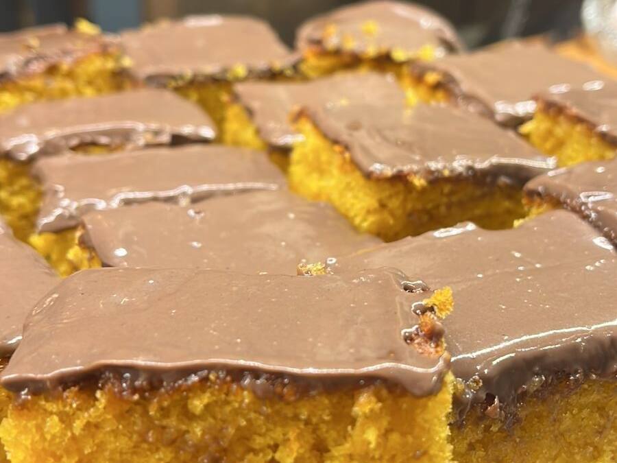 A tray of square-shaped cakes with a golden-brown crust, placed on a glass serving dish.