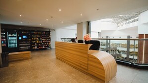 Ein moderner Empfangsbereich mit einem gebogenen Holzbüro, einer großen Auswahl an abgefülltem Wasser und Blick ins Innere des Gebäudes.