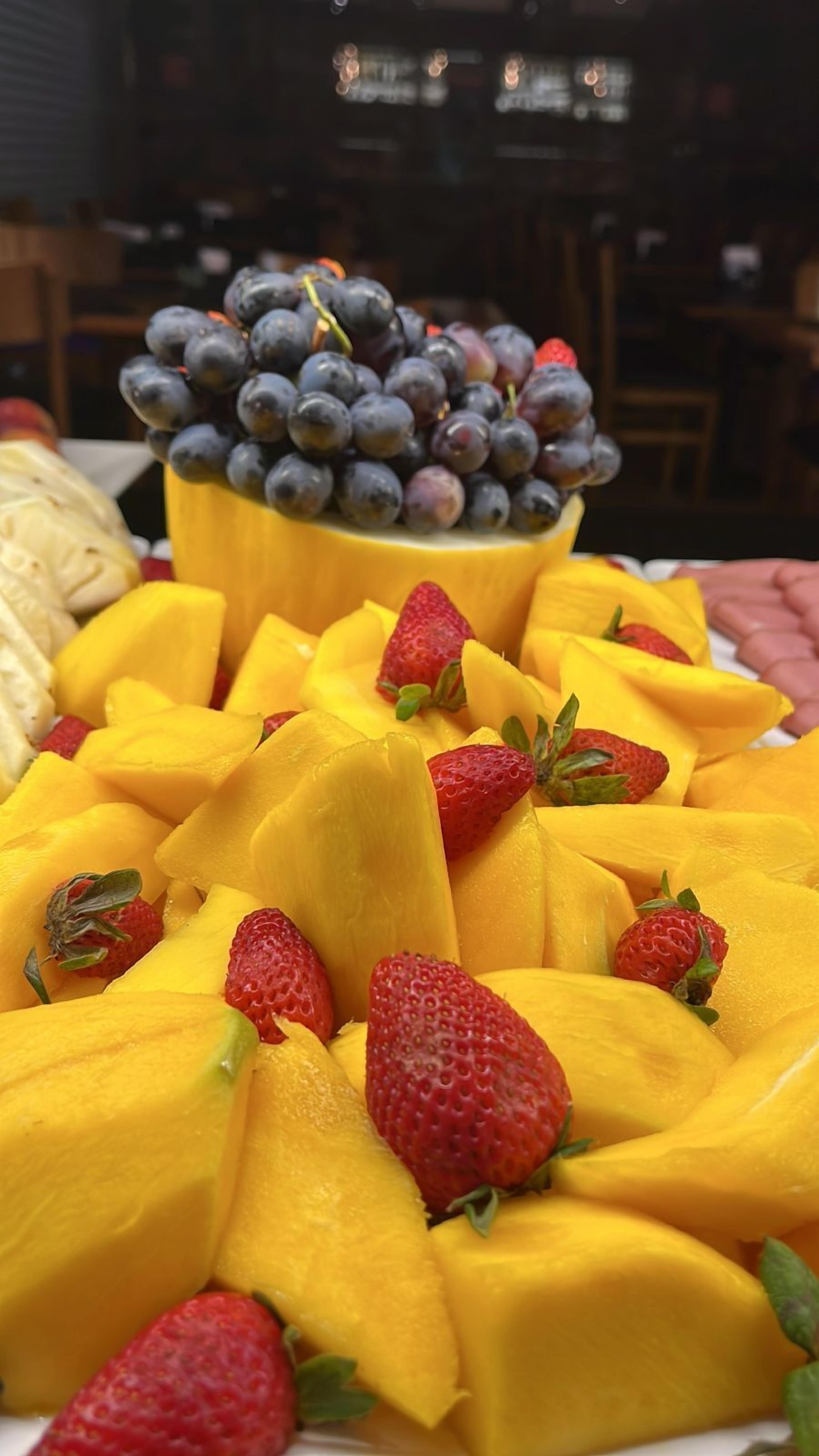 A fruit platter with mango slices and strawberries, and a bowl of grapes.