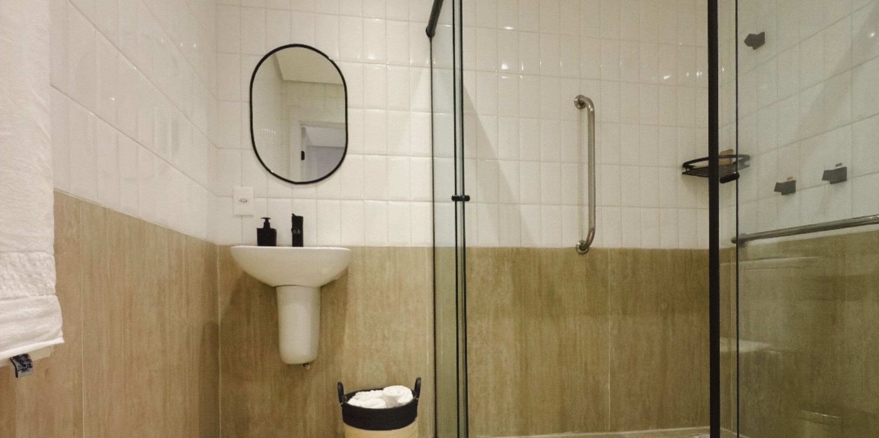 A bathroom with a glass shower enclosure, a white sink, and a mirror.