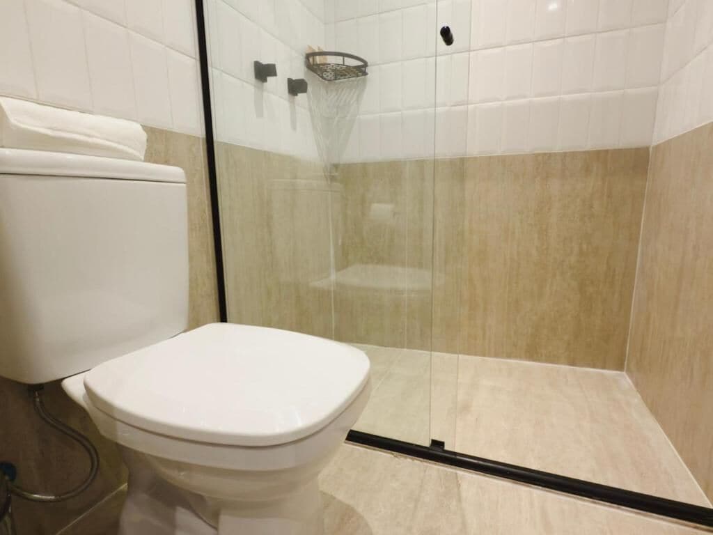 A modern bathroom with a glass-enclosed shower, a toilet, and a tiled floor.