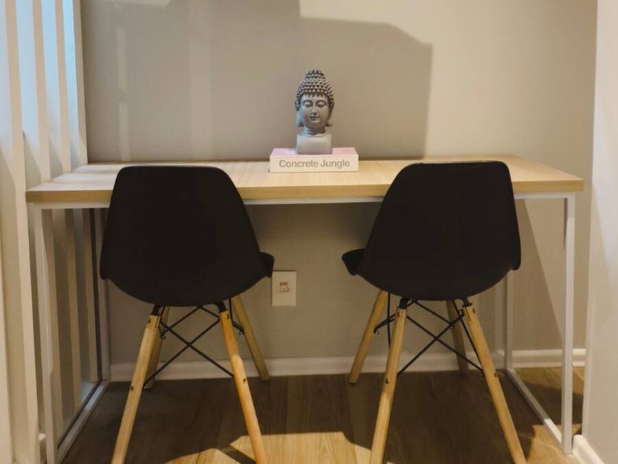 A desk with a bust sculpture labeled "Concrete Jungle" and two black chairs.