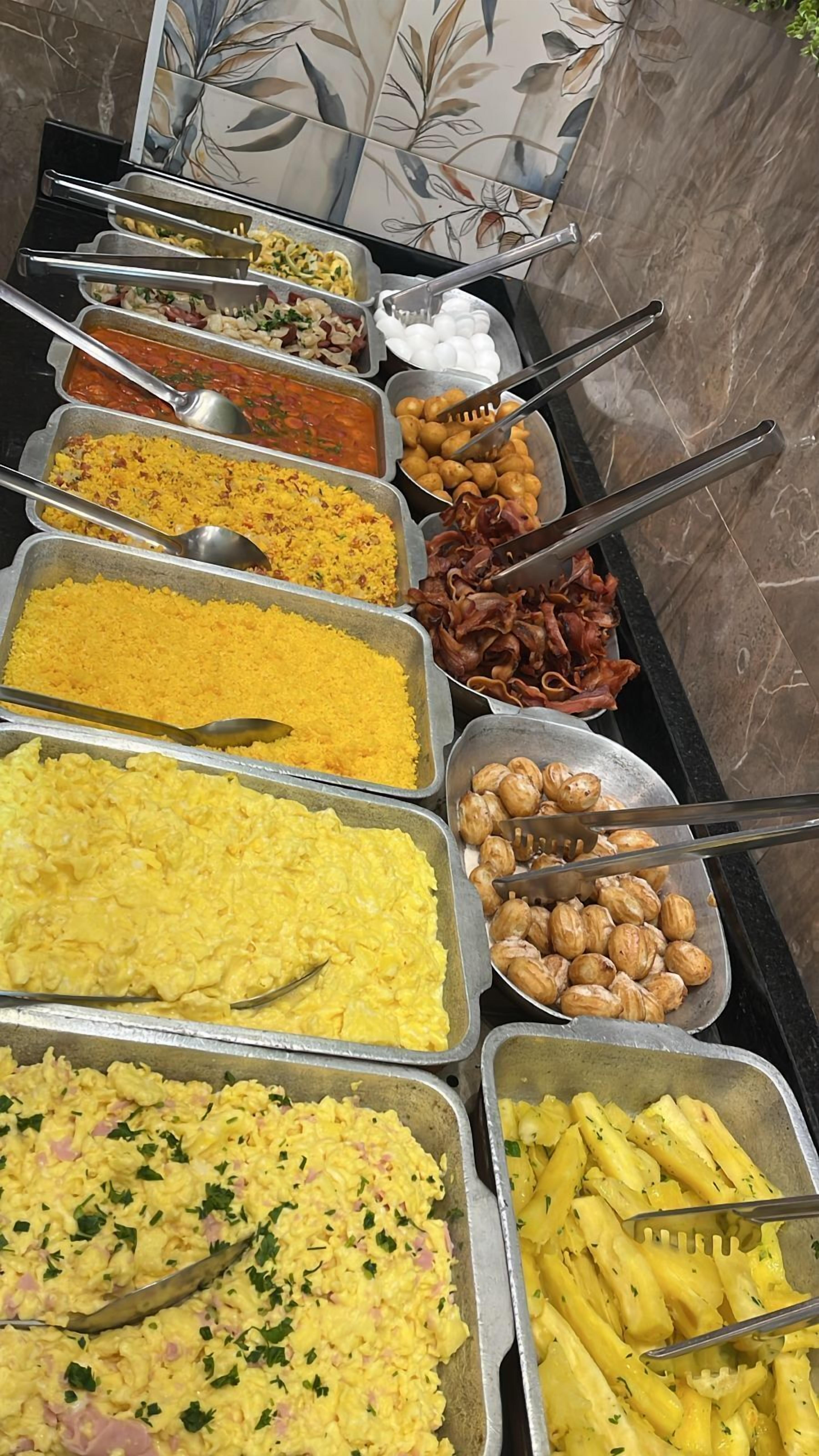 A buffet with various dishes including scrambled eggs, rice, and different types of meat.