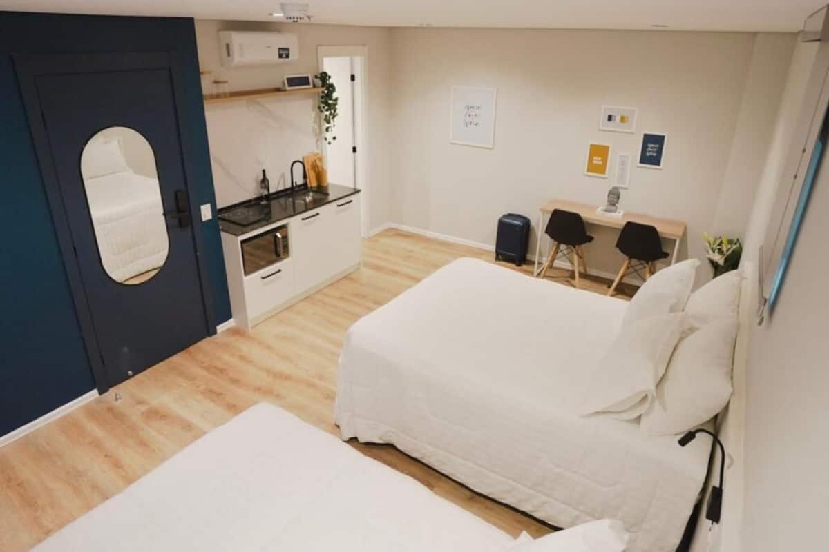 Ein kleines Zimmer mit Bett, Schreibtisch und einer Küchenzeile.