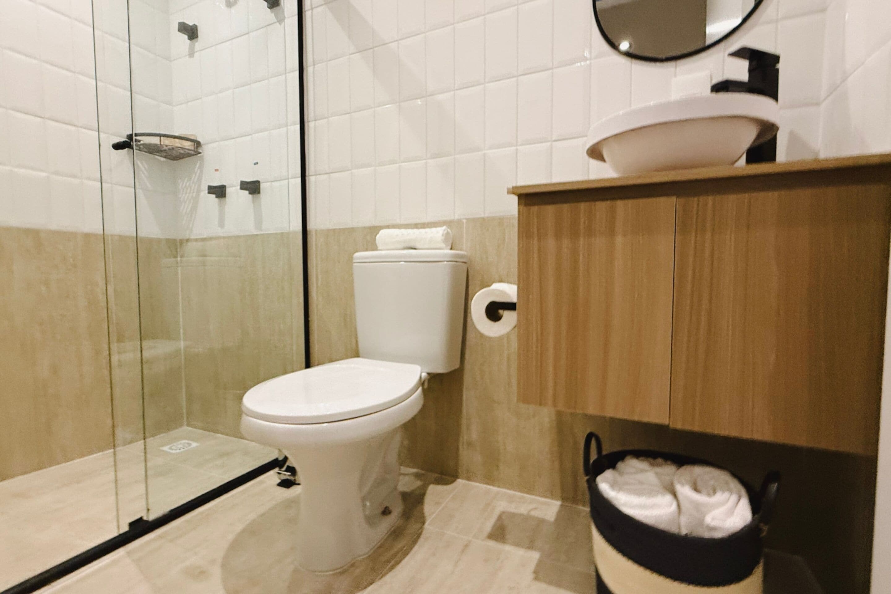 Une salle de bain moderne avec une douche à parois de verre, des toilettes blanches et un meuble-lavabo en bois avec un évier.