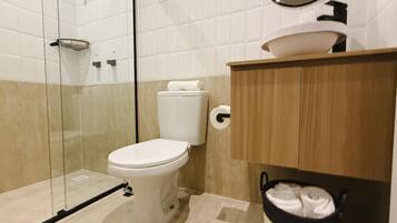 Une salle de bain moderne avec une douche à parois de verre, des toilettes blanches et un meuble-lavabo en bois avec un évier.