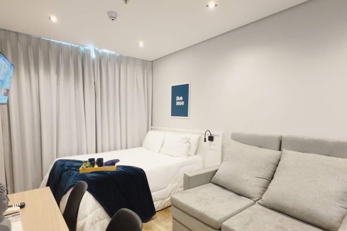 Ein modernes Hotelzimmer mit Bett, Sofa, Schreibtisch und Fernseher.
