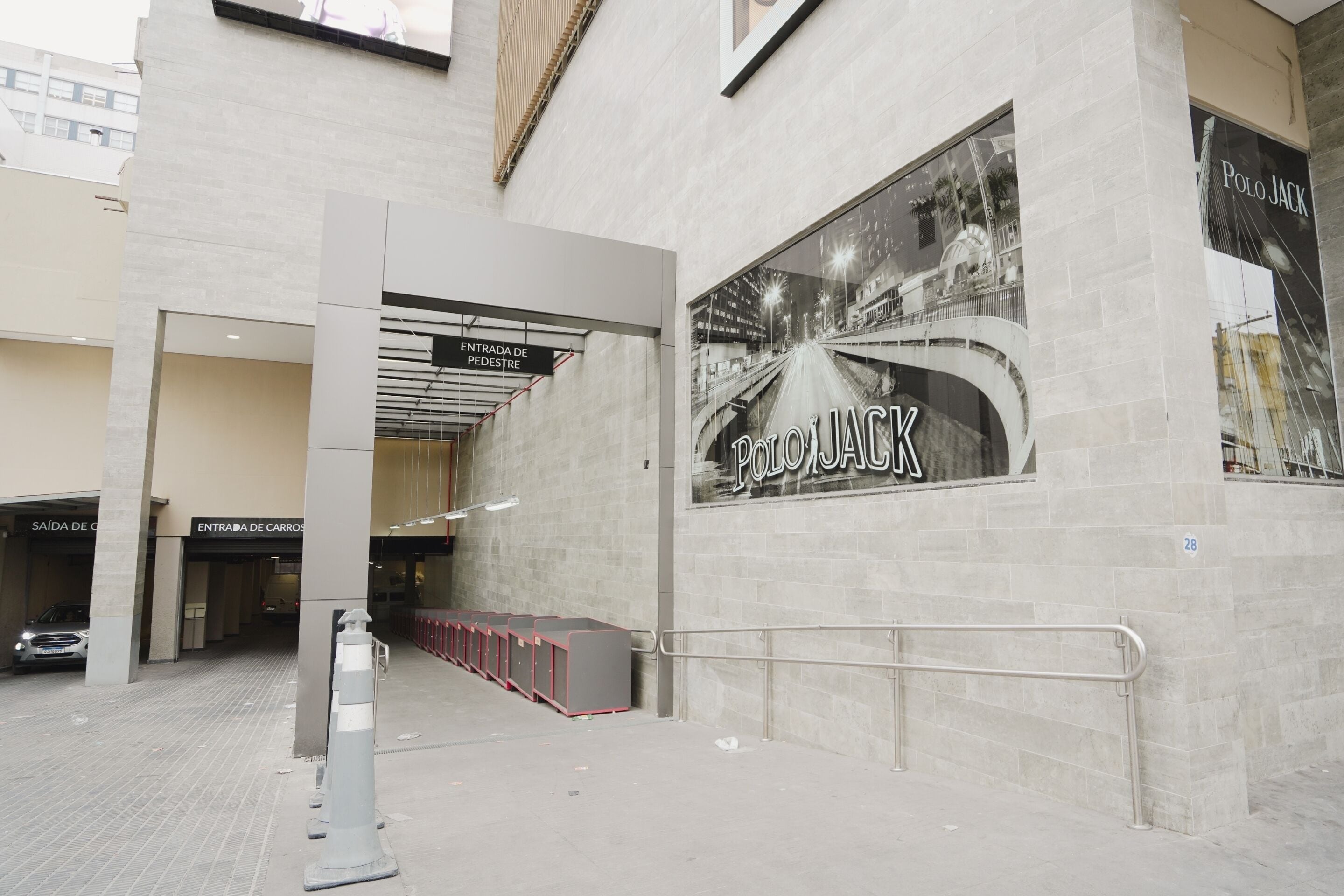 A modern building entrance with a large 'POLO JACK' sign, a covered pedestrian walkway, and a car entrance.