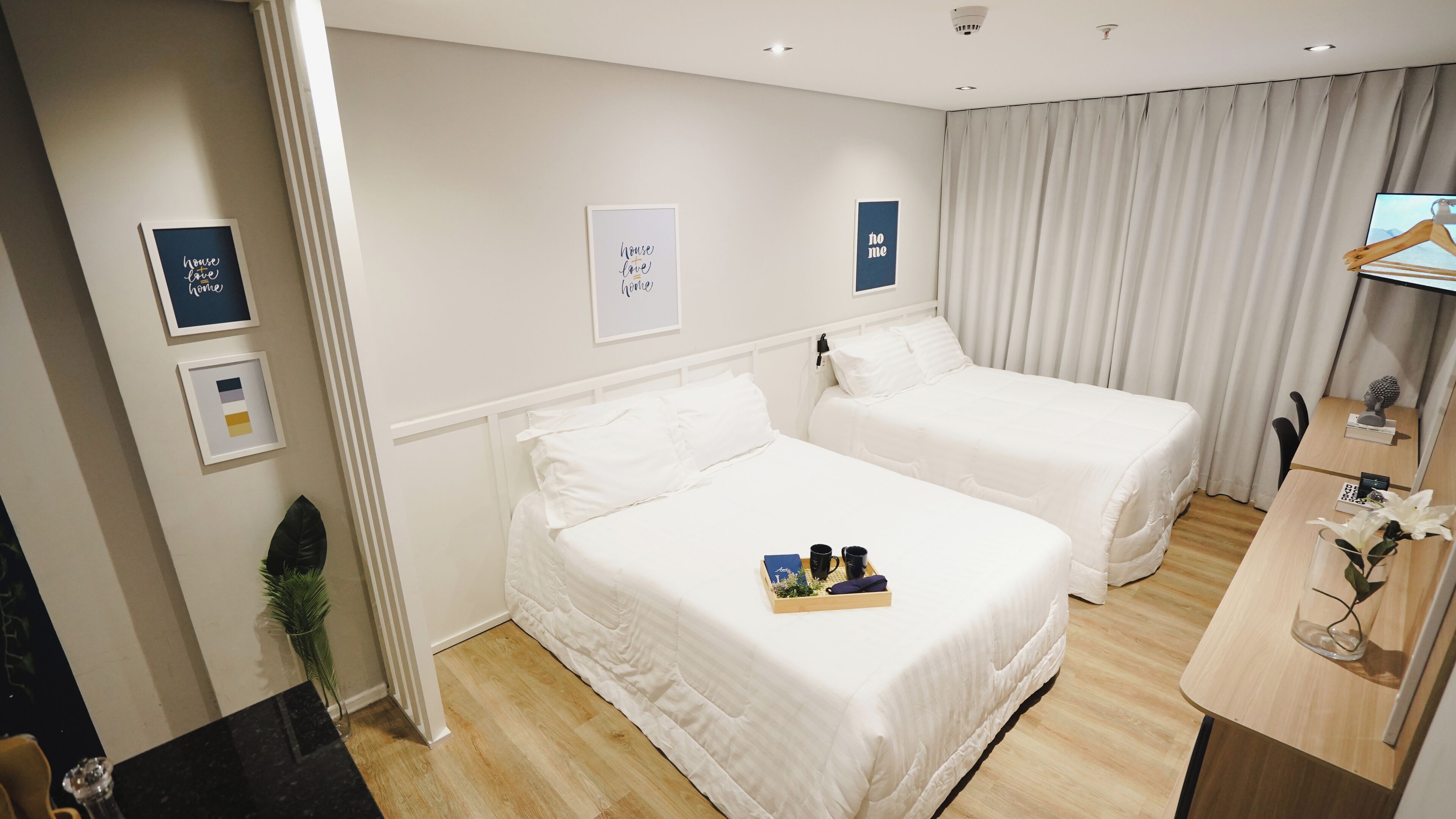 Een hotelkamer met twee bedden, een bureau, een stoel, een plant en wanddecoratie.