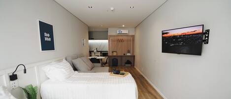 Habitación de hotel con dos camas, un escritorio, una silla, una kitchenette pequeña y vistas a la ciudad.