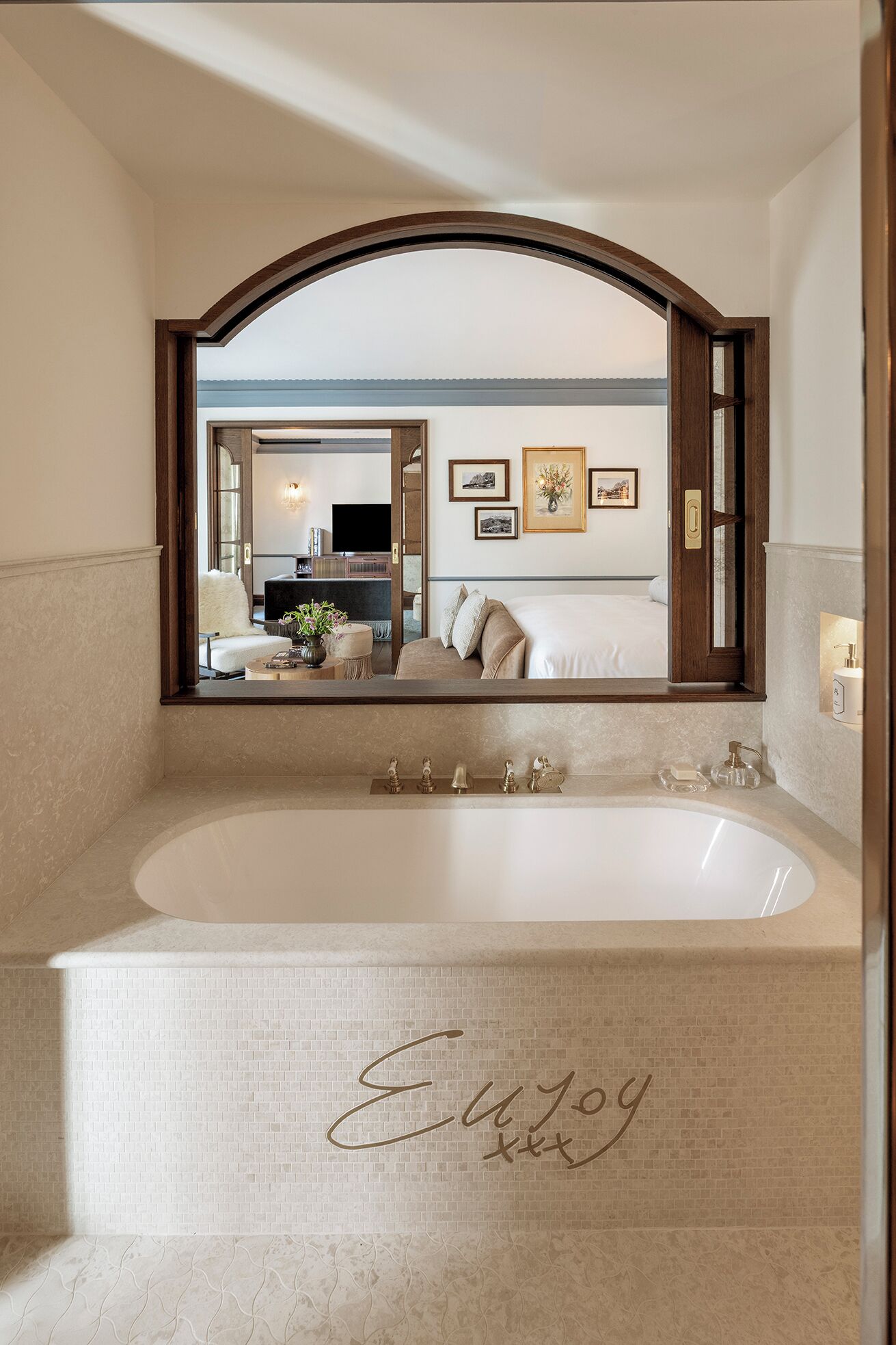 Une salle de bain avec une grande baignoire, un miroir et un mur orné d’un tableau encadré.