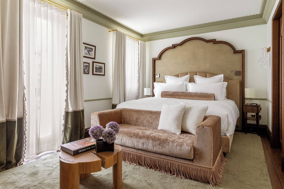 A hotel room with a large bed, a sofa, a small side table, and a lamp.