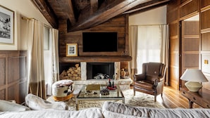 A cozy living room with a fireplace, a leather armchair, and a glass coffee table. - Ancora Cortina (Cortina d'Ampezzo)