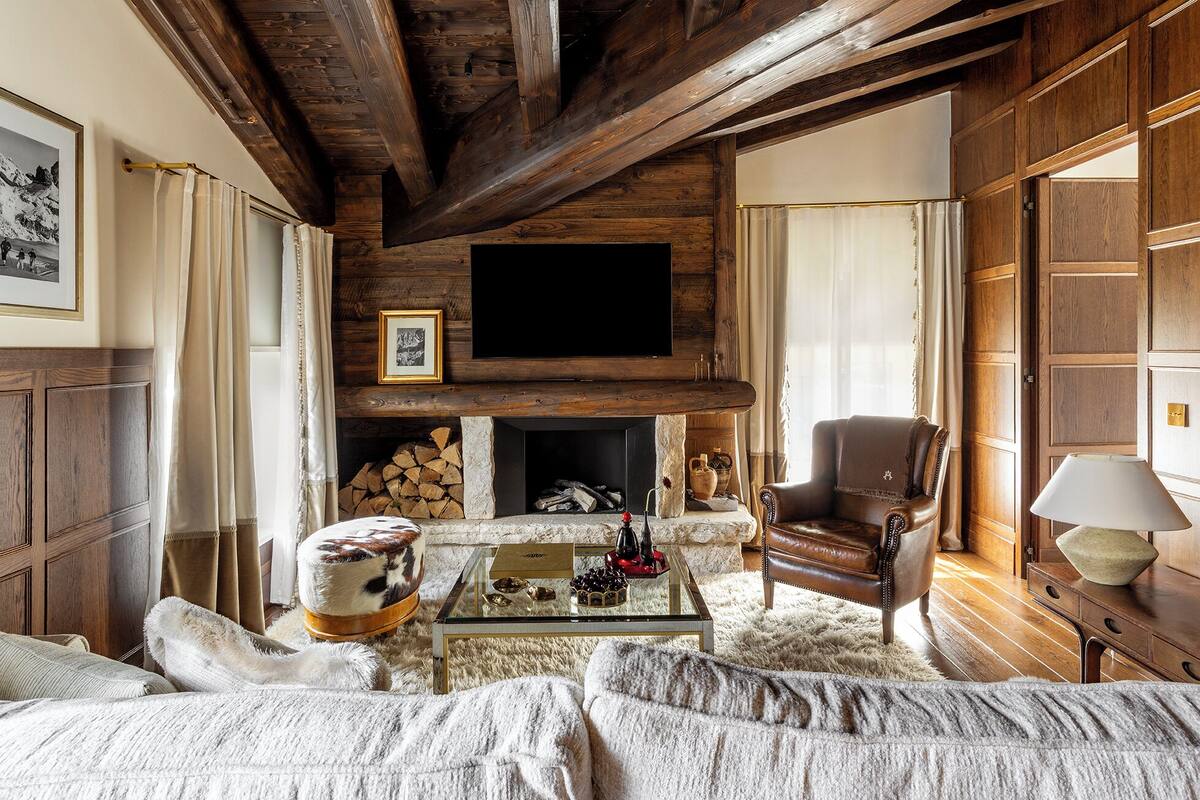 A cozy living room with a fireplace, a leather armchair, and a glass coffee table.