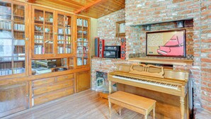 A room with a brick wall, wooden bookshelves, a piano, and a television. - Burney Cottage w/ Game Room: Walk to Town! (Burney)
