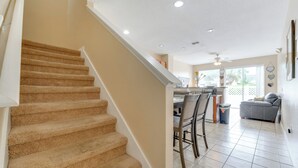A staircase leading to a kitchen area with a dining table and chairs. - 4 Mi to Disney! Family Townhome w/ Pool Access (Kissimmee)