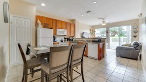 A spacious kitchen with wooden cabinets, a white refrigerator, and a dining area with chairs. - 4 Mi to Disney! Family Townhome w/ Pool Access (Kissimmee)