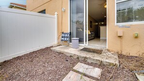 A residential property with a covered patio, a sliding glass door leading to a living area, and a white fence. - 4 Mi to Disney! Family Townhome w/ Pool Access (Kissimmee)