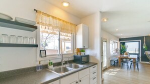 A modern kitchen with a granite countertop, stainless steel sink, white cabinets, and a microwave. There is a dining area with a wooden table and chairs. - Water Views & Close to Beach: Home in Lake Havasu (Lake Havasu City)