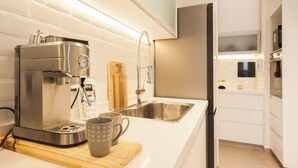A modern kitchen with a coffee maker, a sink, and a cutting board with a mug.