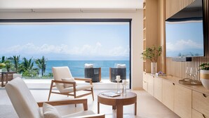 Un salón moderno con un amplio ventanal corredera que da a un balcón con vista al mar.