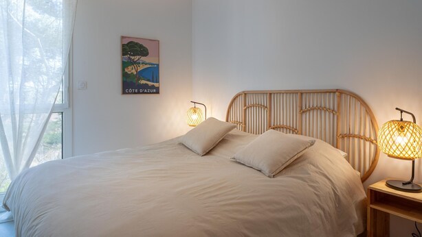 Ein Schlafzimmer mit einem Bett, zwei Nachttischlampen, einer Wandleuchte und einem Poster.