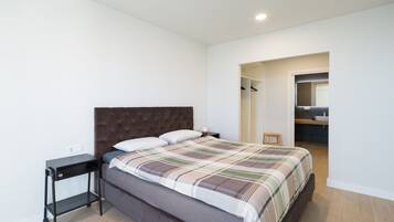 A bedroom with a bed, a nightstand, a wardrobe, and a bathroom visible through an open door.