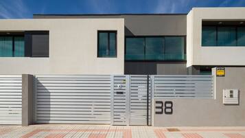 A modern building with a grey facade, a gated entrance, and a number '38' on the wall.