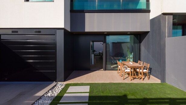 A modern house with a garage, a dining area with a table and chairs, and a well-maintained lawn. - Sunset Beach Chalet in Pozo Izquierdo Gran Canaria (Santa Lucia)