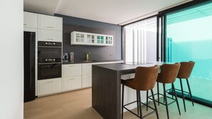 A modern kitchen with white cabinets, a black countertop, and a large window offering a view of the sea. - Sunset Beach Chalet in Pozo Izquierdo Gran Canaria (Santa Lucia)