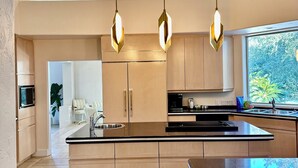 Uma cozinha moderna com ilha central, armários de madeira e luminárias pendentes.