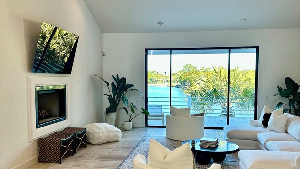 Sala de estar ampla com uma grande janela, lareira e vista para o mar.