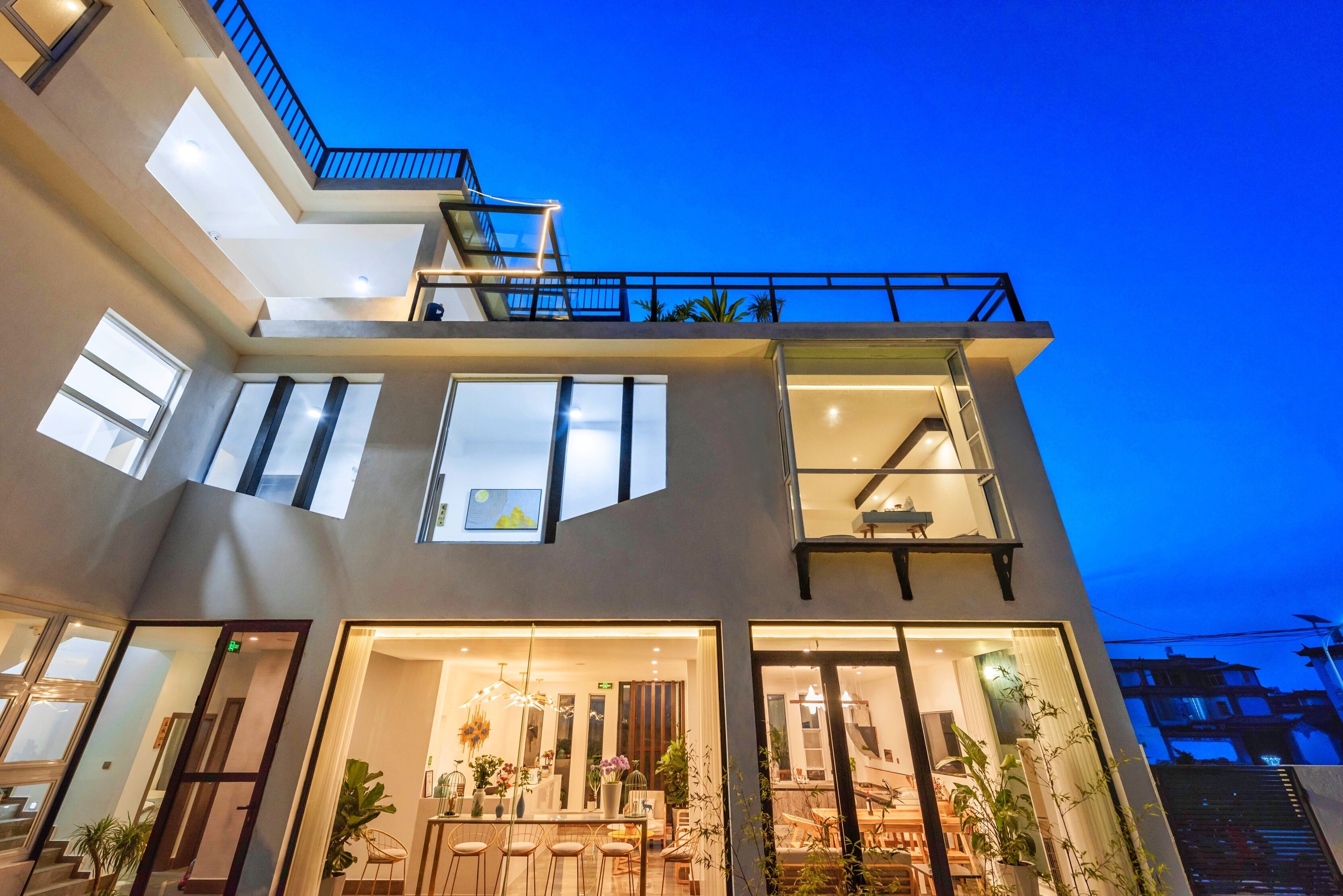 Un hôtel moderne à plusieurs étages, doté d’une façade en verre, d’un espace extérieur aménagé et d’une terrasse sur le toit.