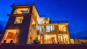 A modern multi-story building with large windows, balconies, and a well-lit entrance. - The Field Inn (Dali)