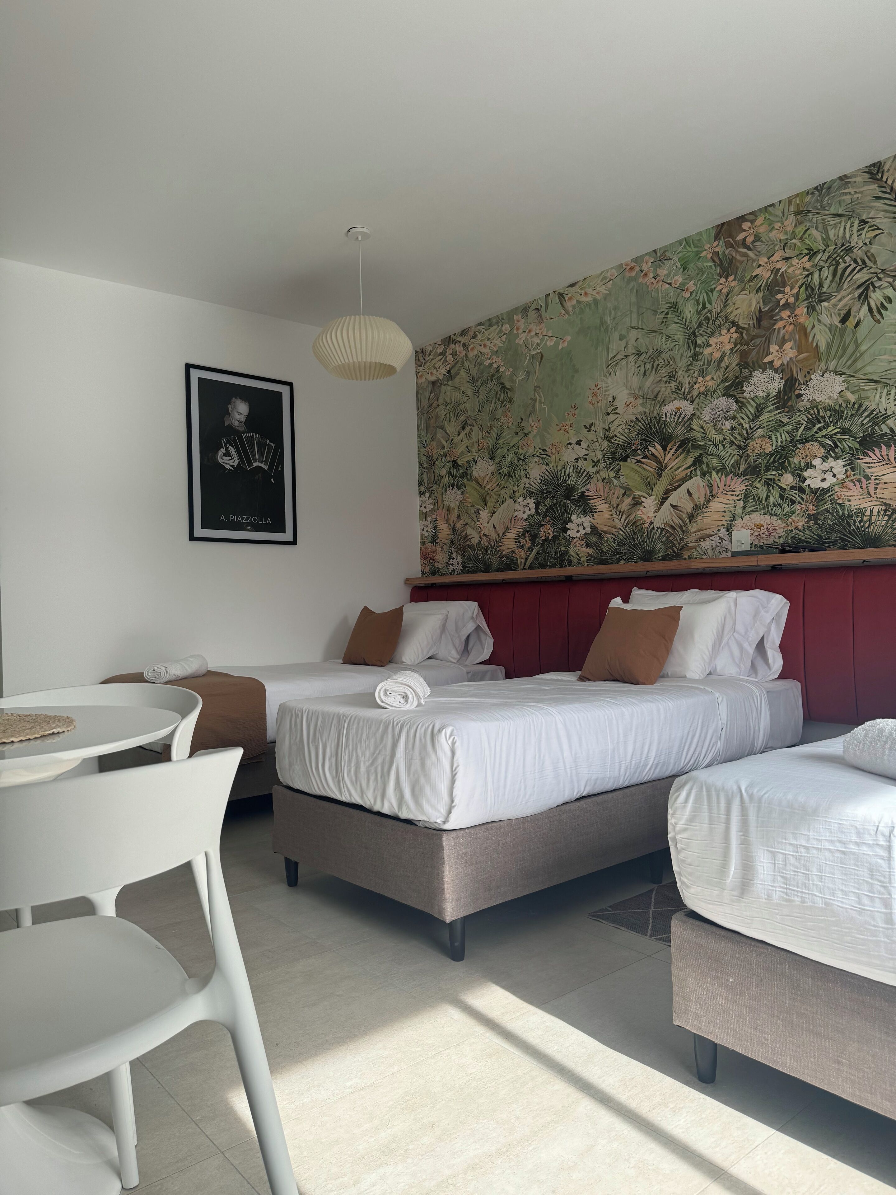 A hotel room with two beds, a dining table, and a large floral wall mural.