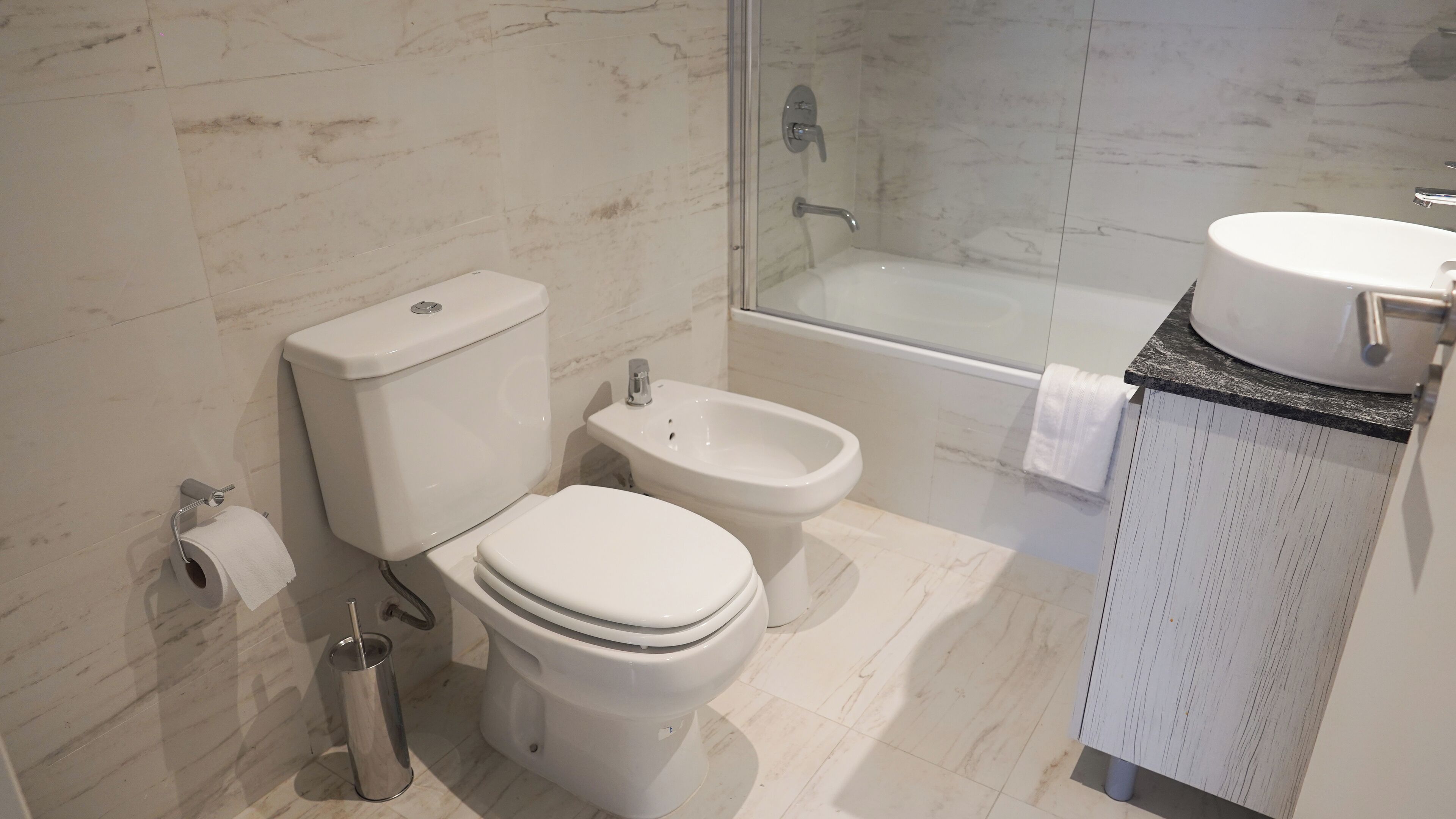 A modern bathroom with a toilet, bidet, and bathtub.